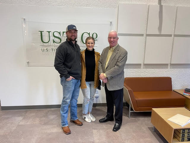 A young couple standing with David Benson at the title company on the day their purchase closed